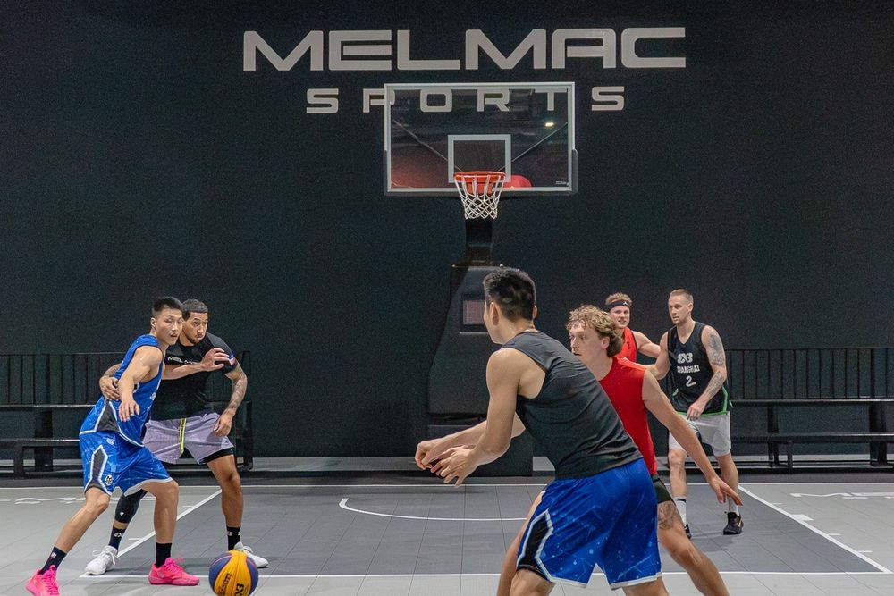 A 3×3 game in play beneath the Melmac Sports wall mark at Imus