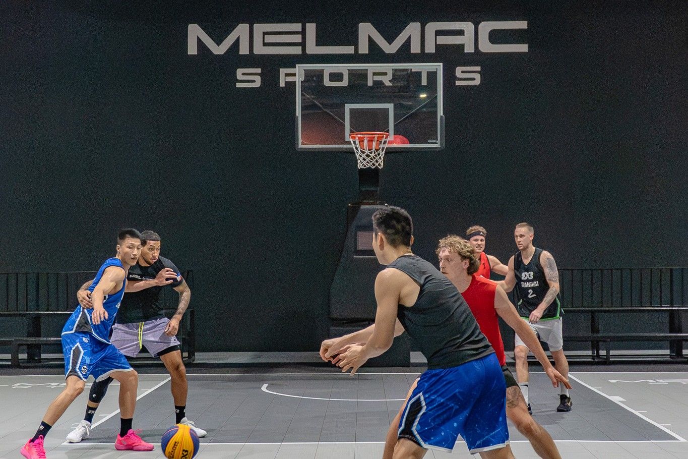 A 3×3 game in play beneath the Melmac Sports wall mark at Imus