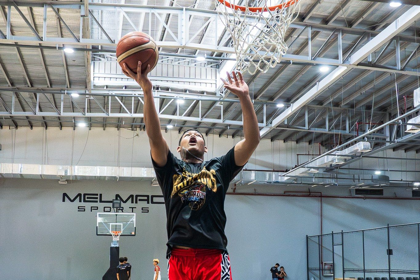 A player finishing at the rim on the Melmac Sports court at Imus