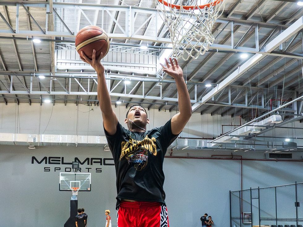 A player finishing at the rim on the Melmac Sports court at Imus