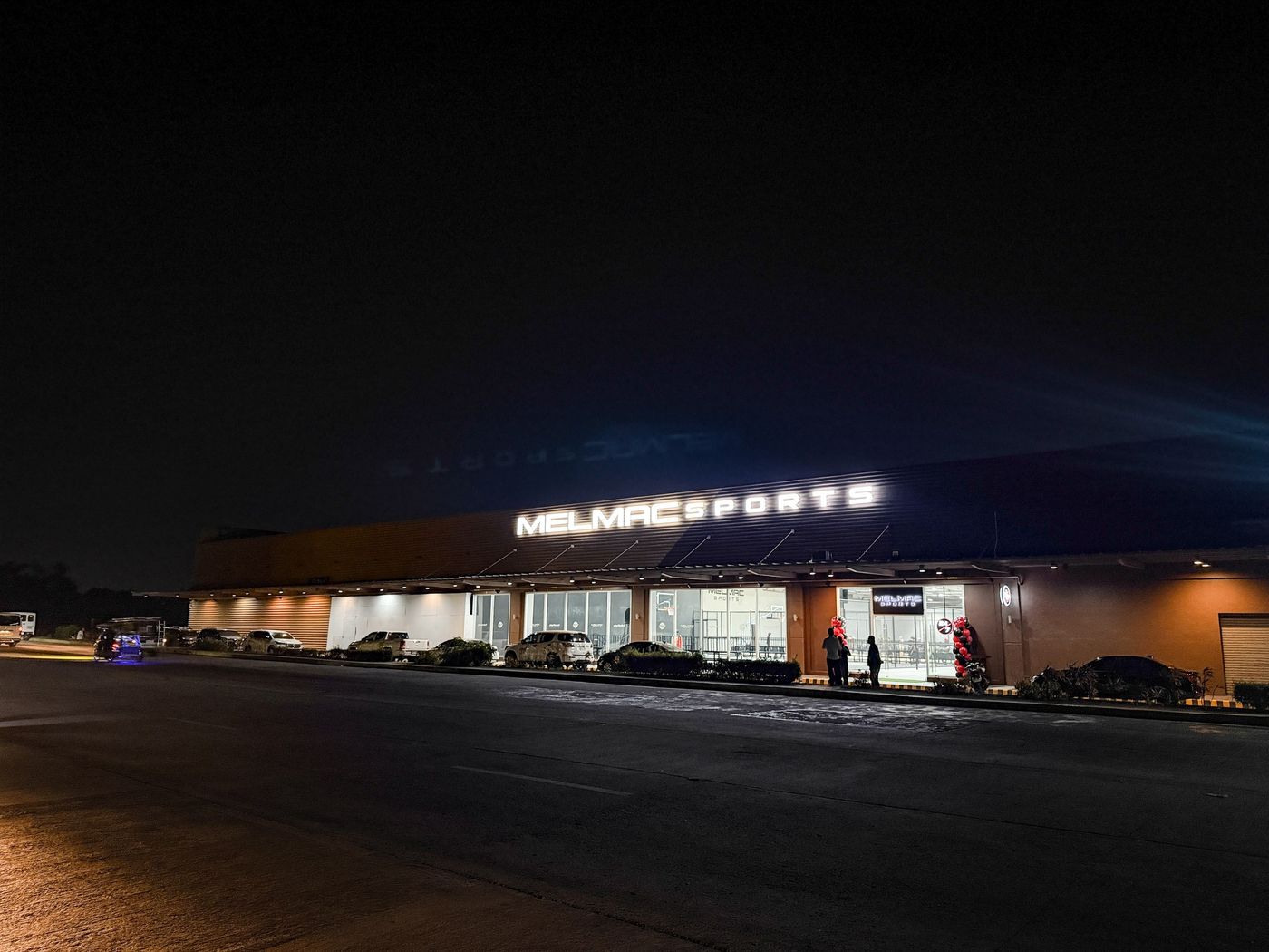 The Melmac Sports Imus building lit along its full frontage at night