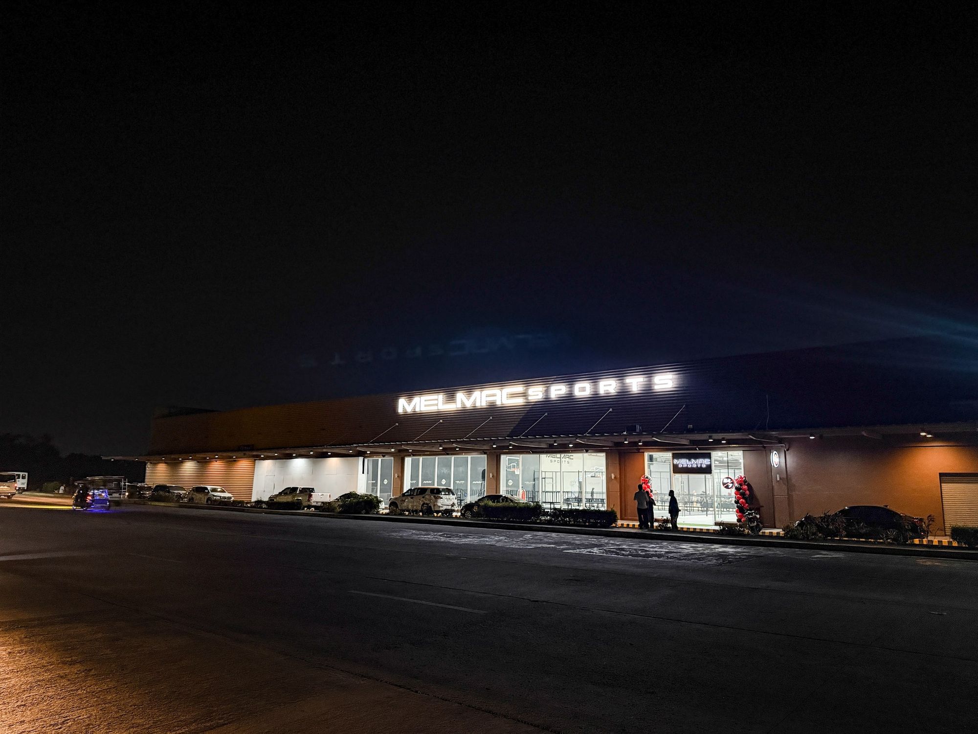 The Melmac Sports Imus building lit along its full frontage at night