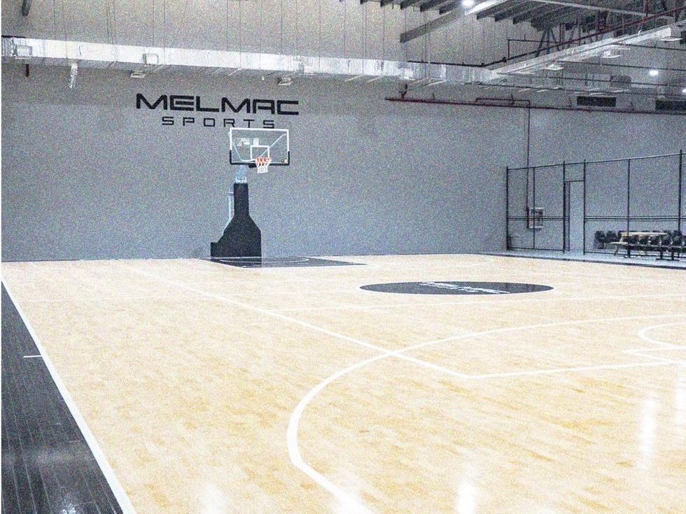 The main 5v5 hardwood court at Imus, with the Melmac Sports wall mark behind the hoop