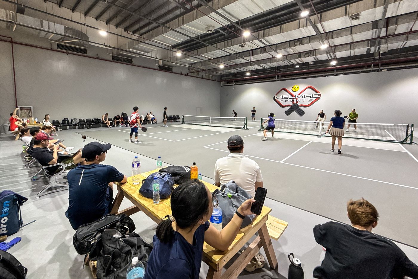 Players and spectators around the indoor pickleball courts at Imus