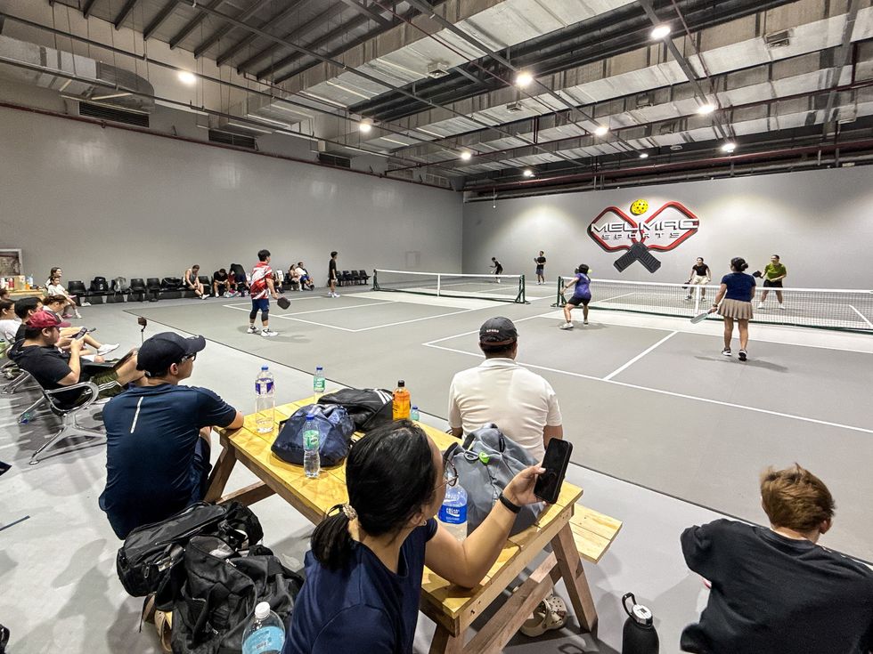 Players and spectators around the indoor pickleball courts at Imus