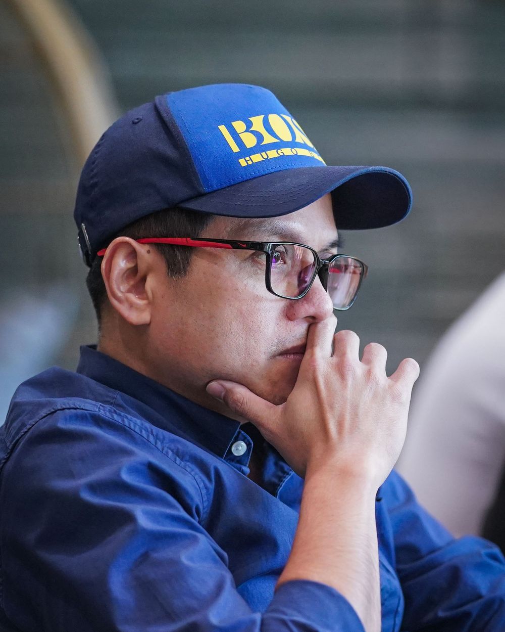 Mel Macasaquit watching a game courtside, hand to his chin