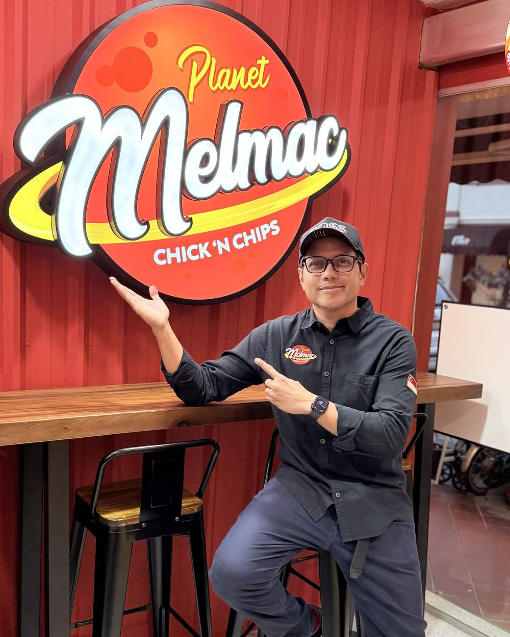 Mel Macasaquit beside the Planet Melmac sign at Imus