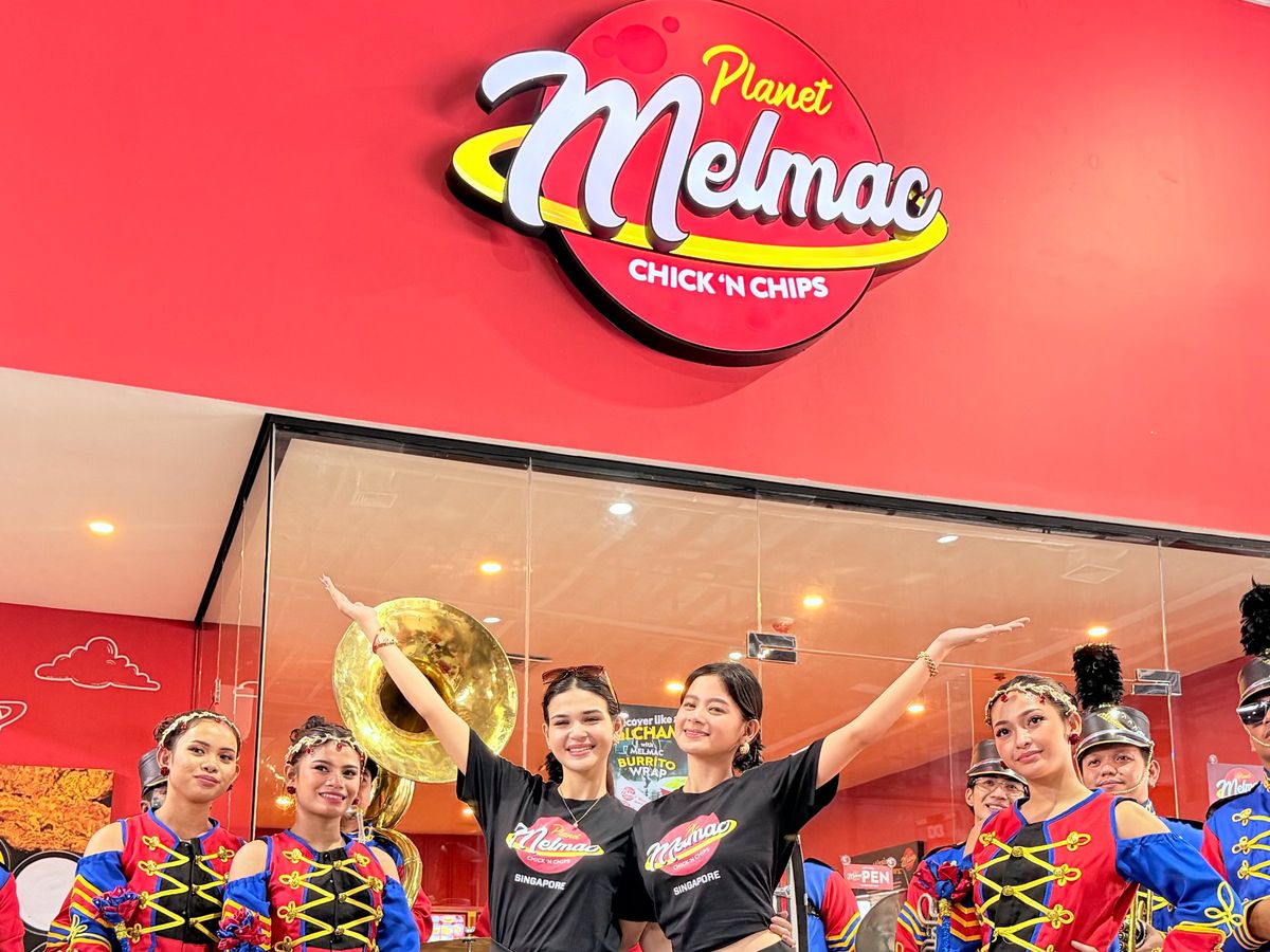 Performers posing beneath the Planet Melmac Chick ’n Chips sign at Imus