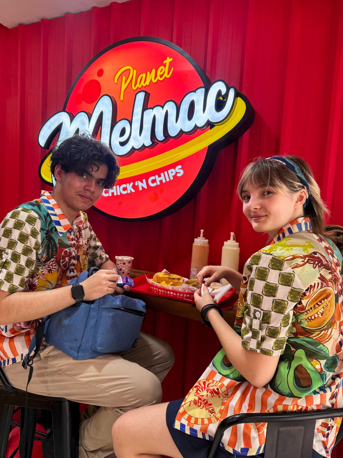 Two customers sharing a tray of chicken and chips at Planet Melmac Singapore