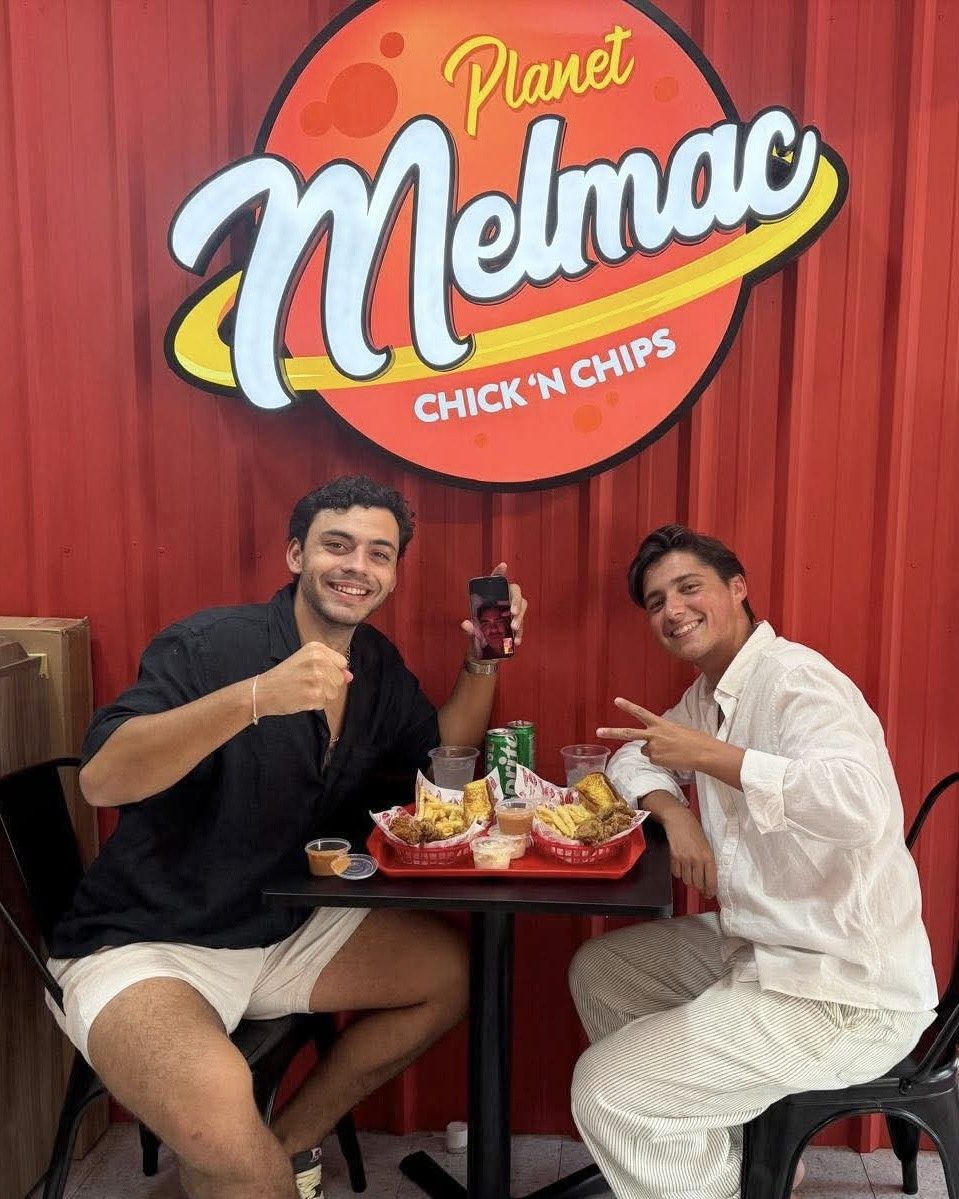 Two customers raising a toast over chicken and chips at Planet Melmac Singapore