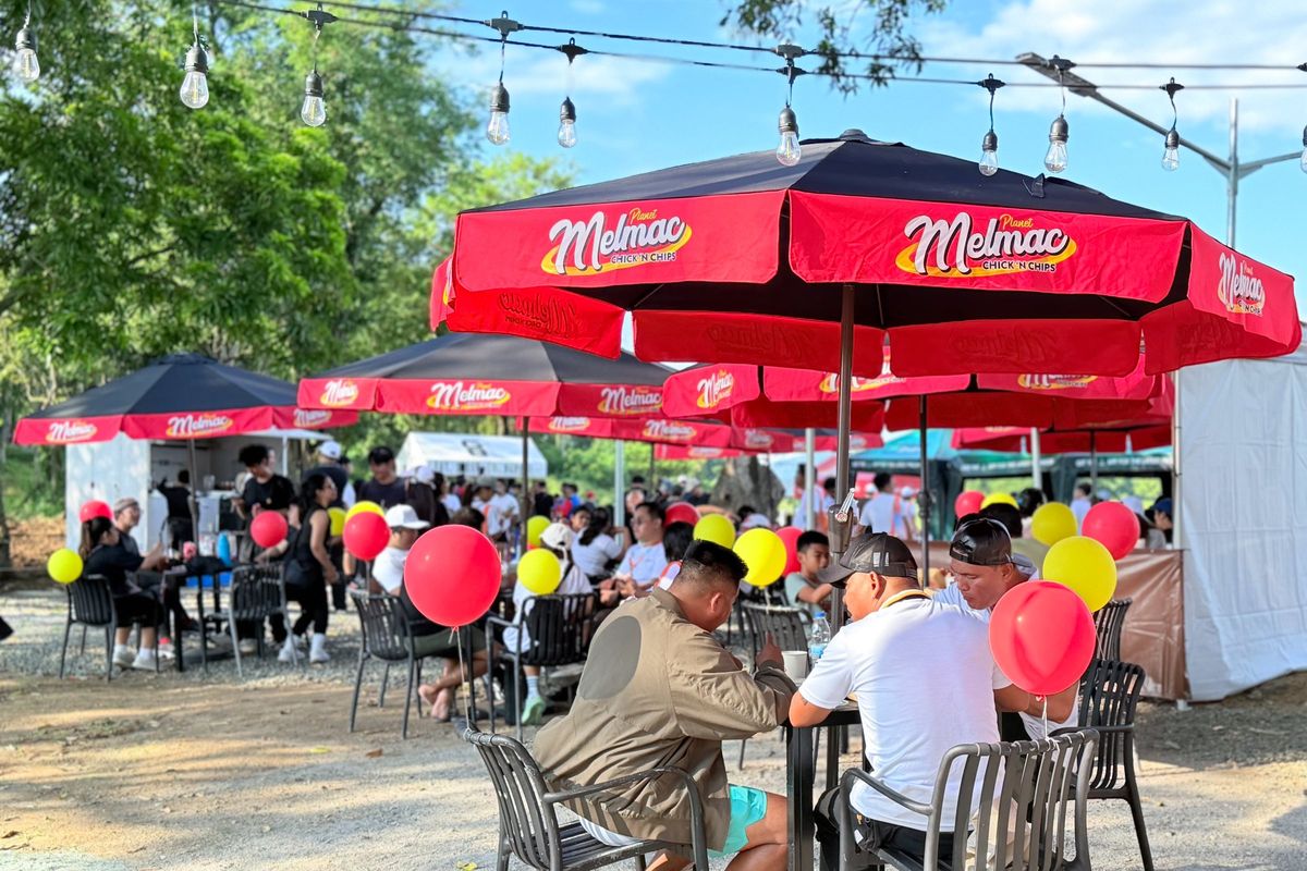 Customers at tables under red Planet Melmac umbrellas at Villar City