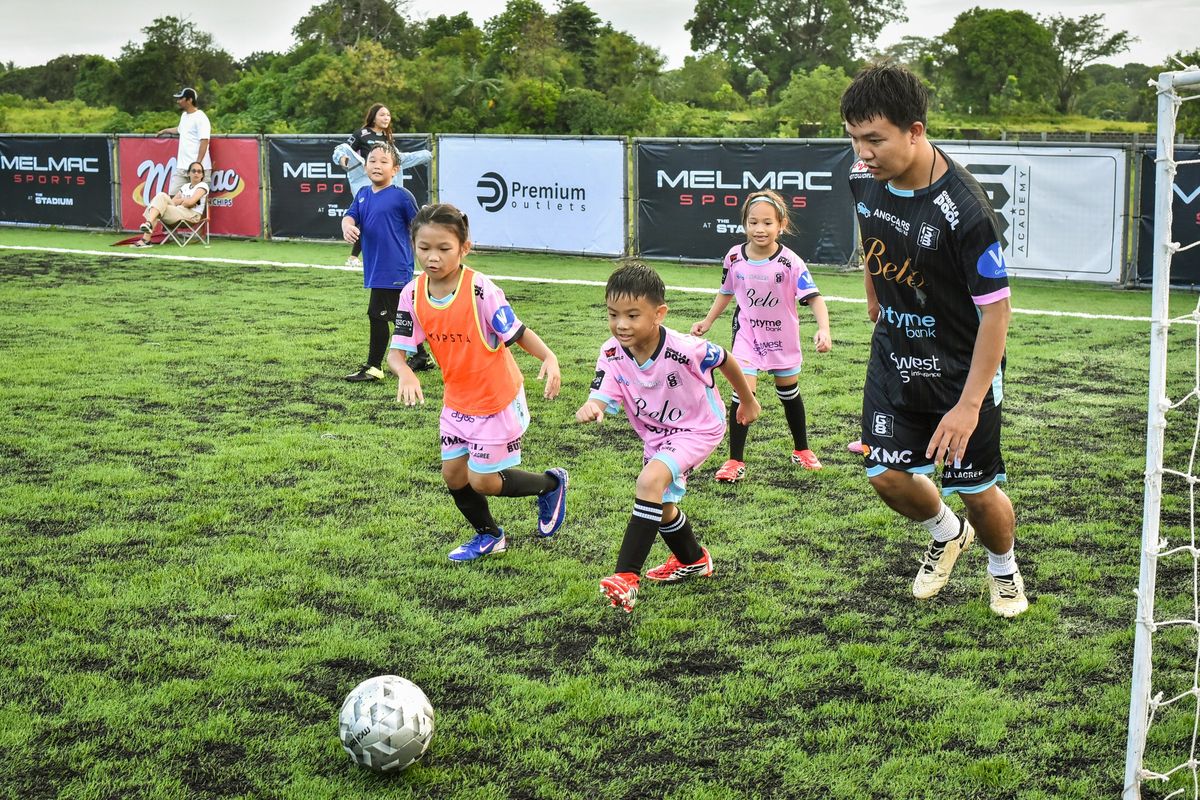 Children dribbling through a drill with a coach at Villar City