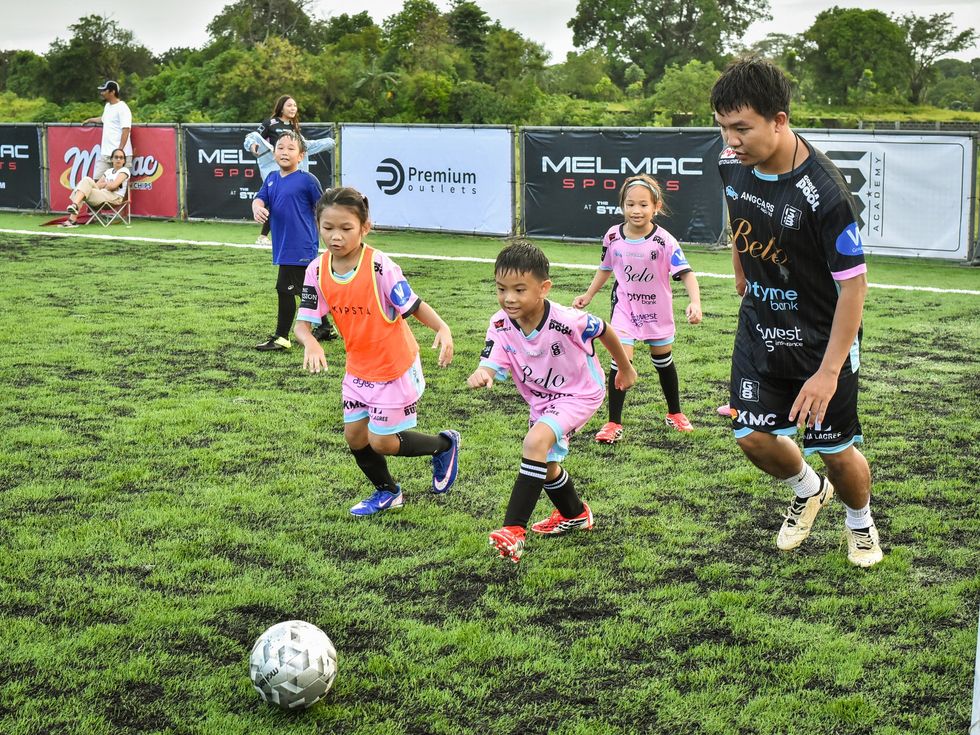 Children dribbling through a drill with a coach at Villar City