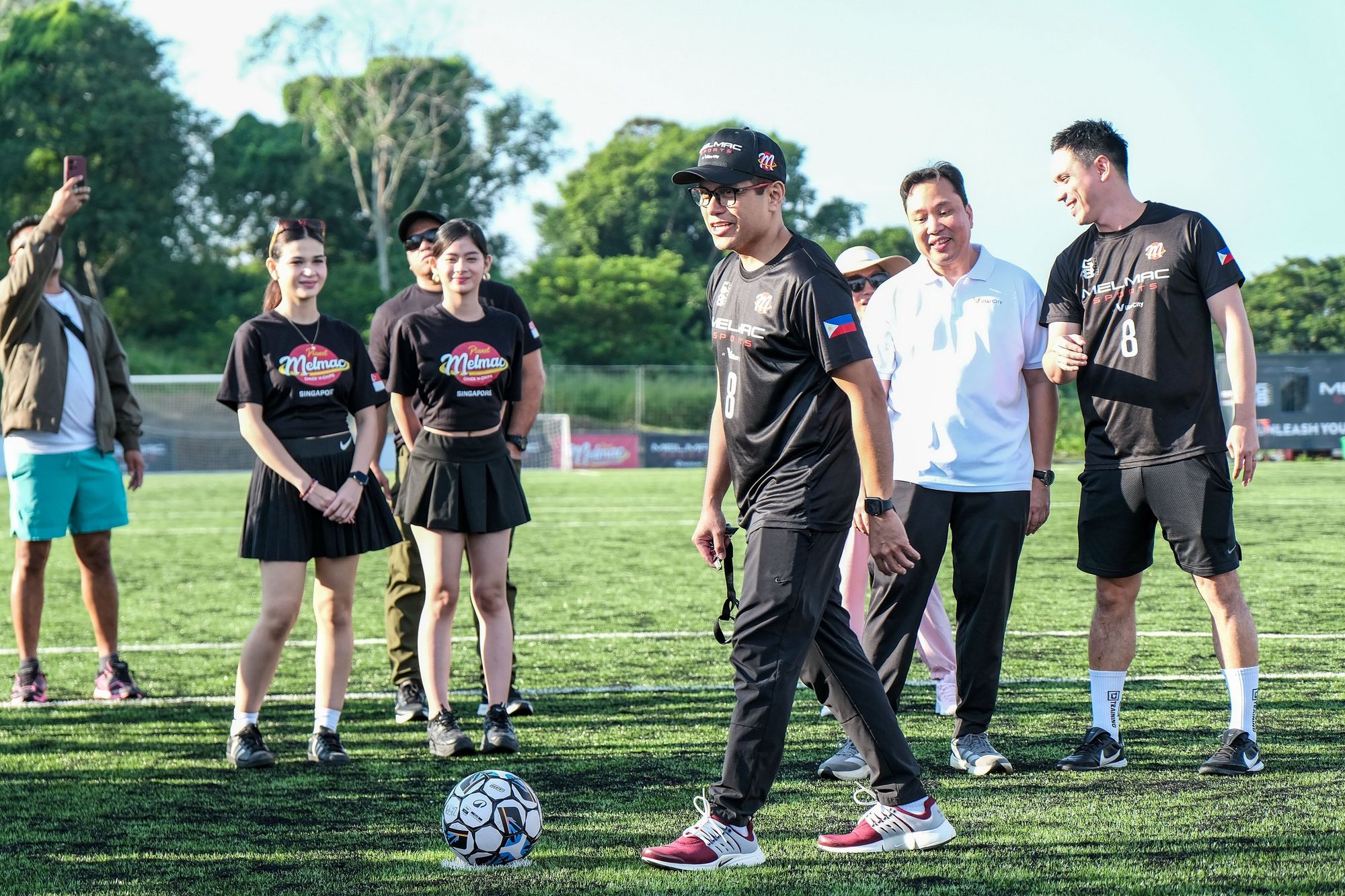 Guests and players watching a ceremonial kick-off on the pitch at Villar City