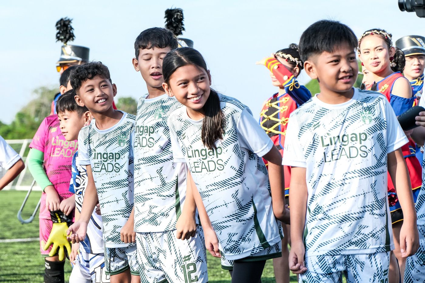 Children in white printed kits smiling for the camera at Villar City