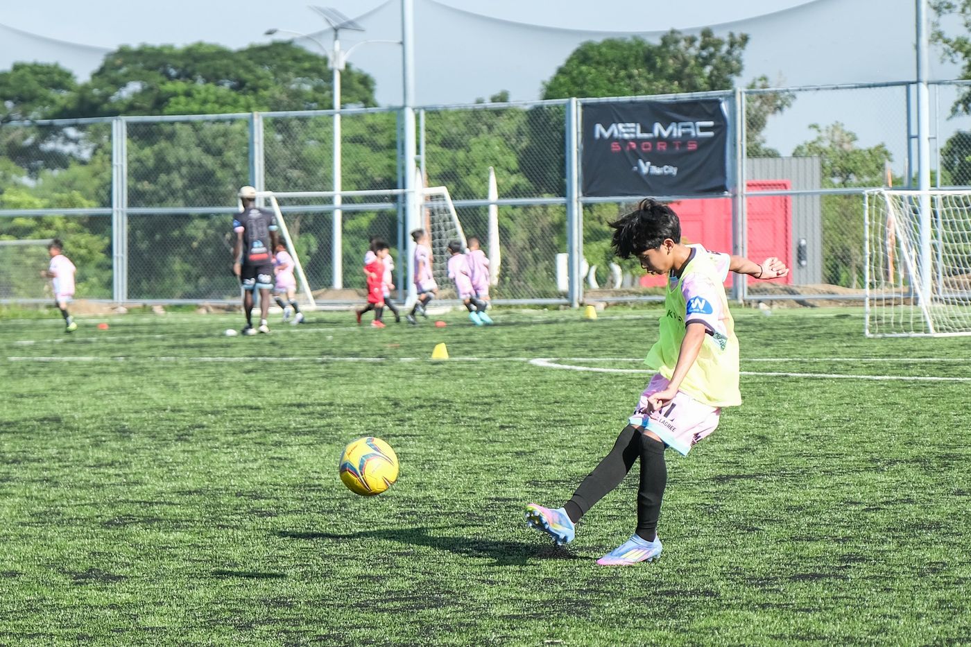 A young player striking the ball on the pitch at Villar City