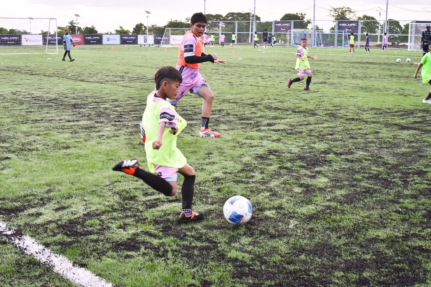A young player striking the ball on the pitch at Villar City