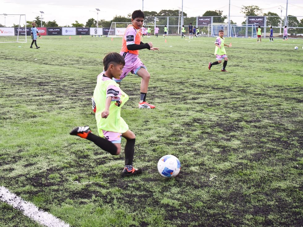 A young player striking the ball on the pitch at Villar City