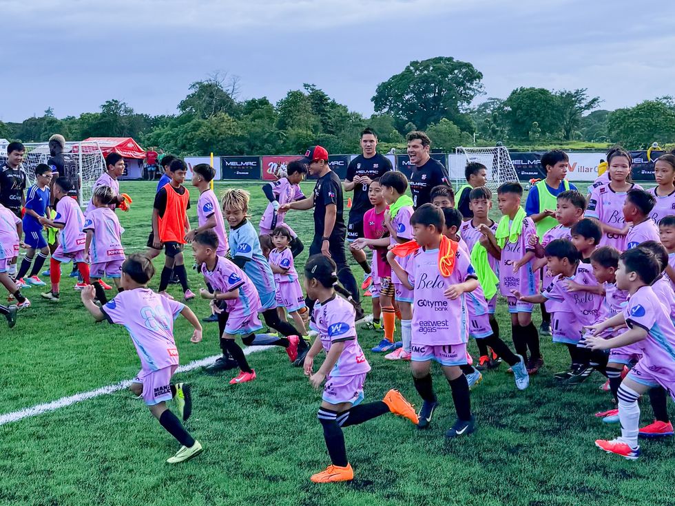 Young players warming up in a group across the pitch at Villar City