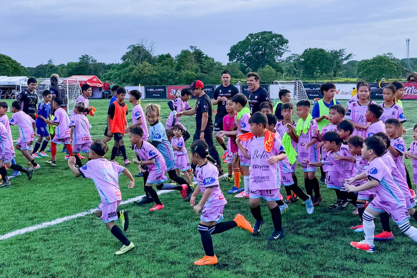 Young players warming up in a group across the pitch at Villar City